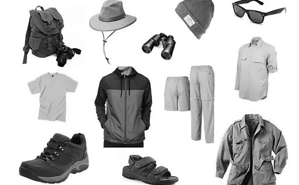 Flat lay of safari packing essentials including clothes, shoes, hat, backpack, sunglasses and sunscreen for a Tanzania safari trip